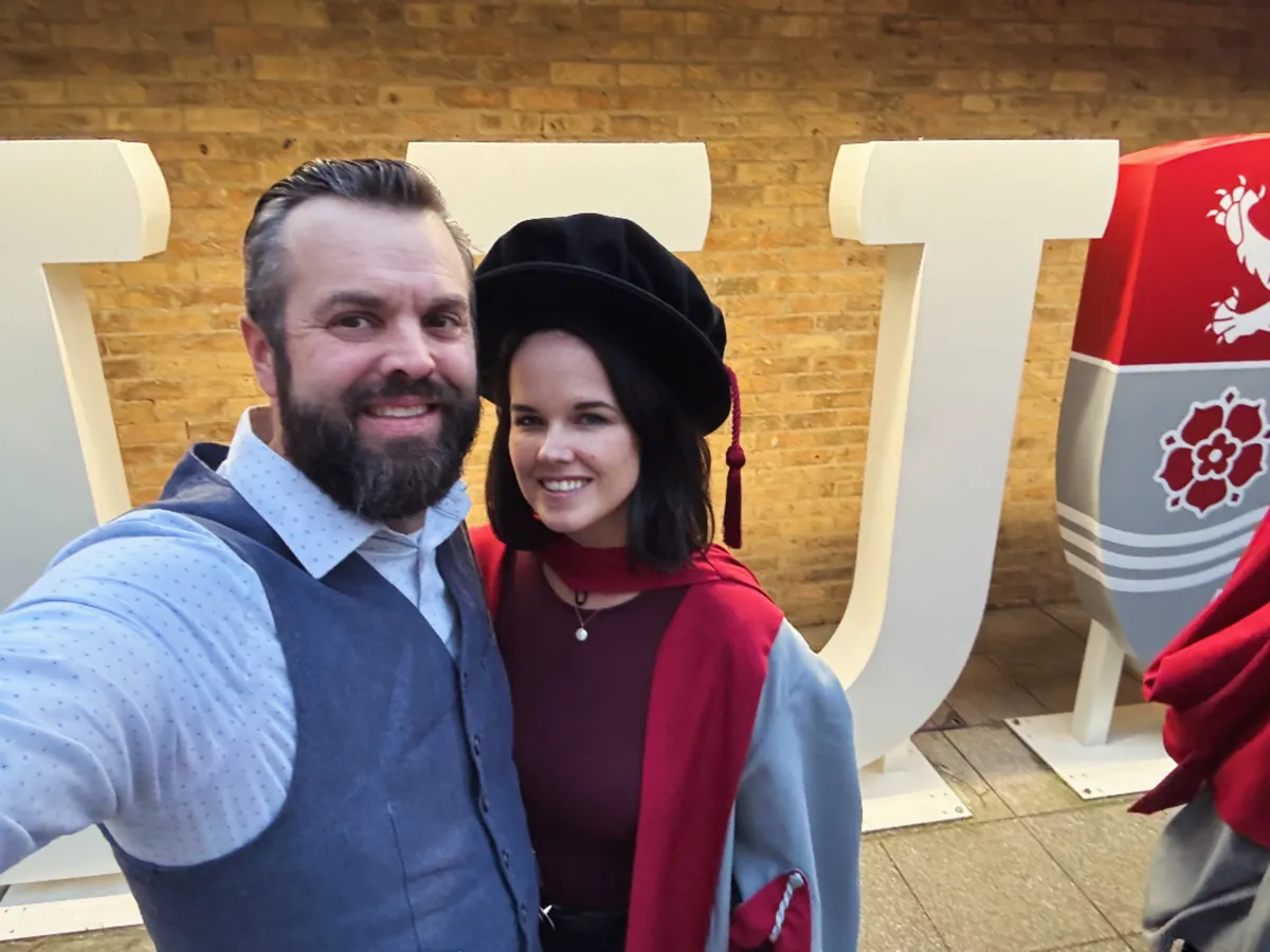 Meredith Guthrie in doctoral robes at her graduation, with her husband Ryan